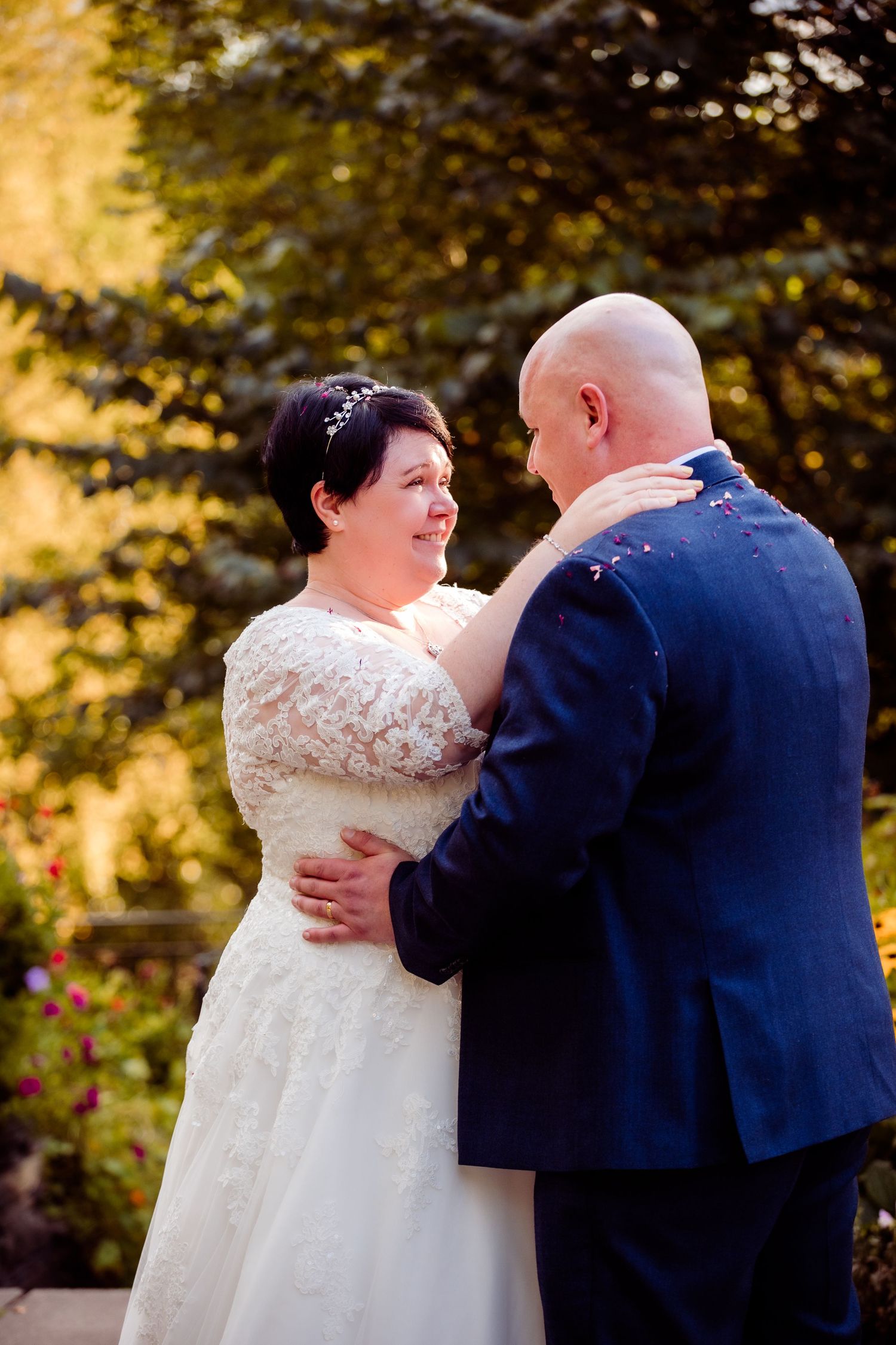 A couple shares an intimate moment in their wedding attire against an autumn backdrop.