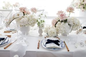 Formal table setting with blue and white china, white flowers, and gold cutlery.