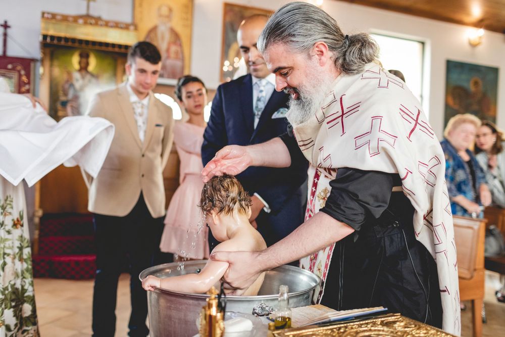 Religious ceremony taking place at decorated altar with traditional Orthodox Christian elements.