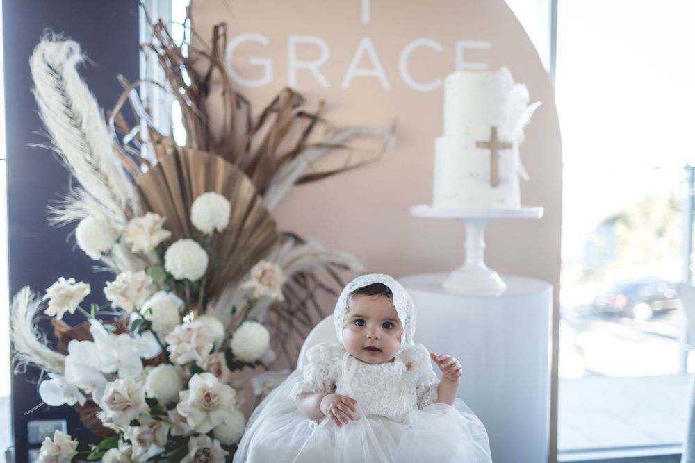 White christening decorations featuring a floral arrangement and cake display.
