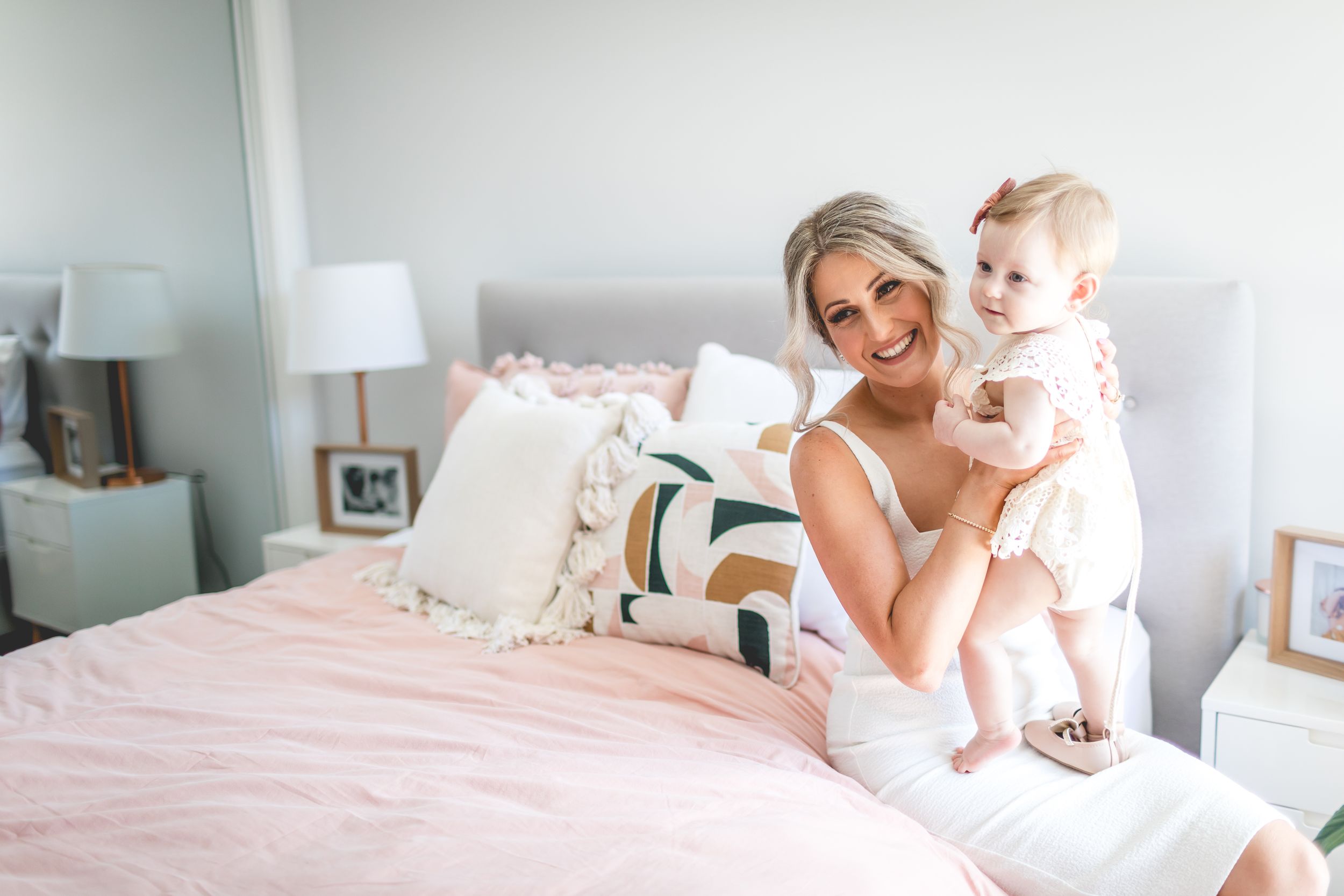 Bright and airy bedroom scene with white bedding and soft pink accents.