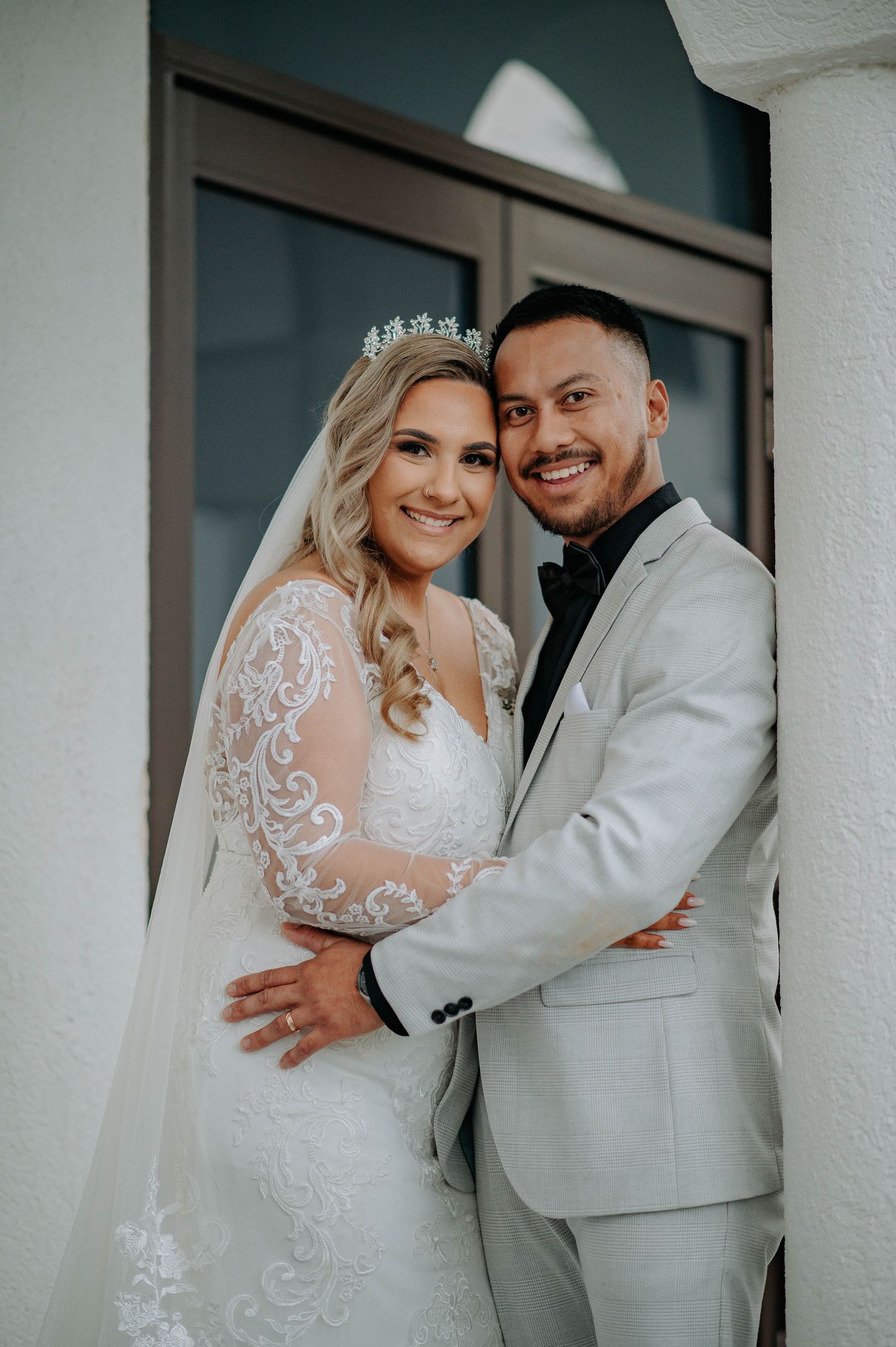 Elegant couple sharing intimate moment in white wedding attire.
