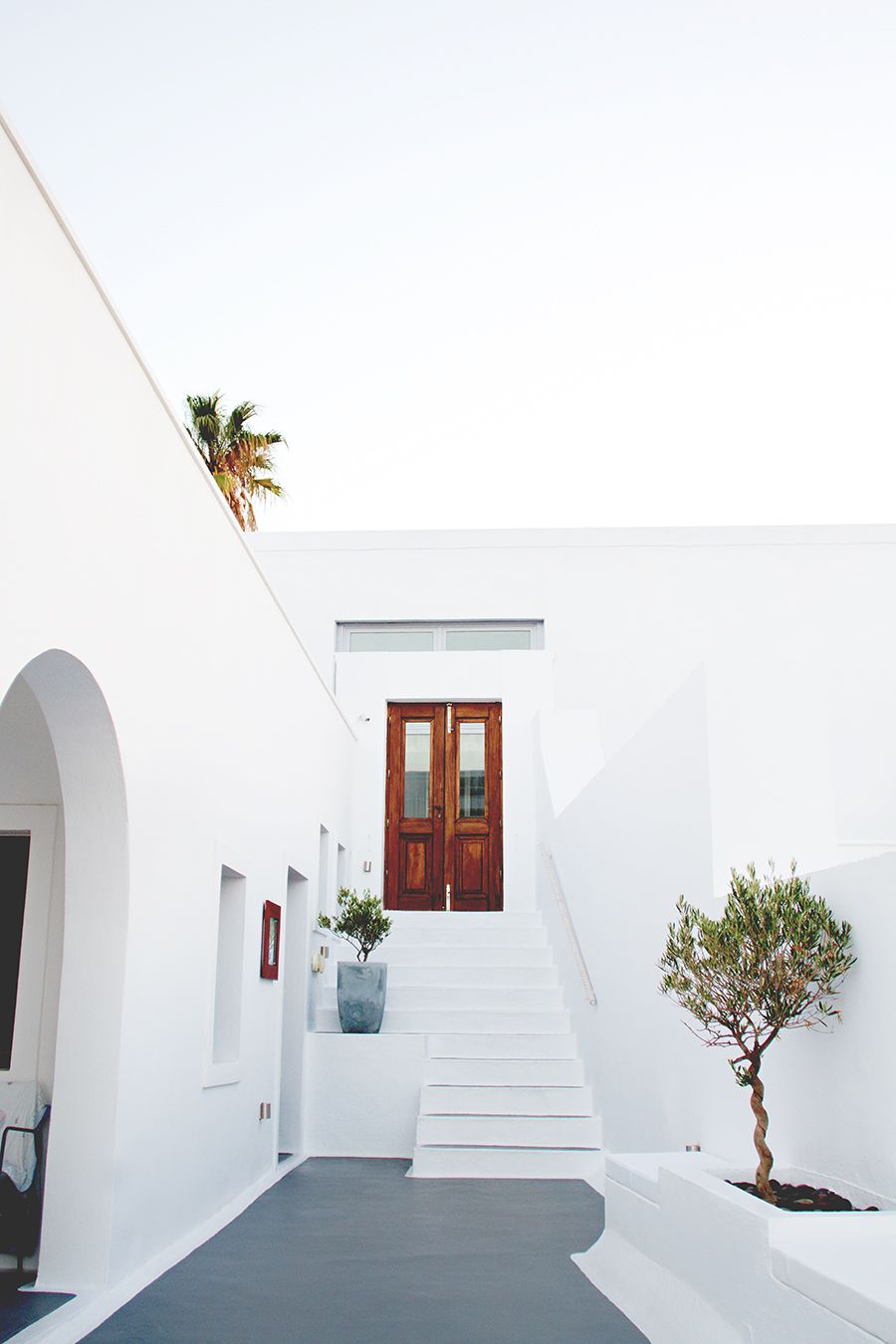 wooden entry doors surrounded in white walls outside of hotel in Santorini, Greece