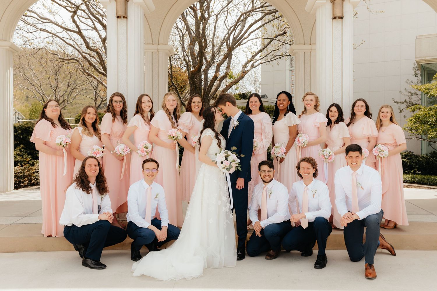 Bridesmaids and groomsmen in pink pose next to bride and groom