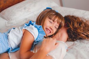 Joyful family moment captured while relaxing together on white bedding.