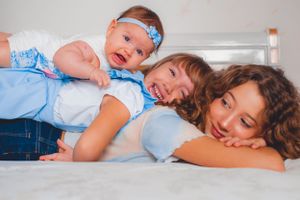 Playful family portrait with everyone laying down and expressing happiness.