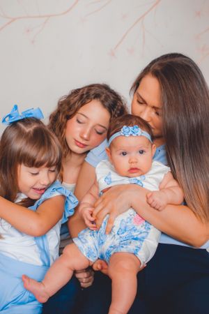 Parents snuggling with baby wearing blue bow and floral dress during intimate photo session.