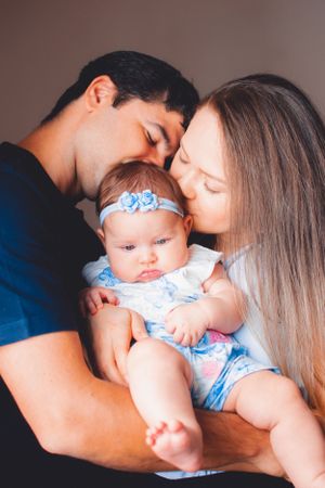 Intimate family portrait with baby wearing blue floral outfit during indoor photo session.