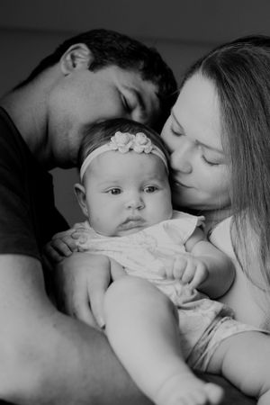 Black and white portrait of tender family moments with baby in soft lighting.
