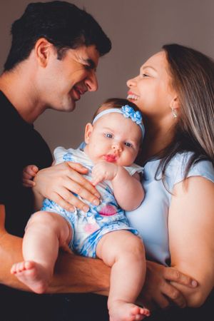 Sweet family portrait session showing affectionate moments with baby in blue floral dress.