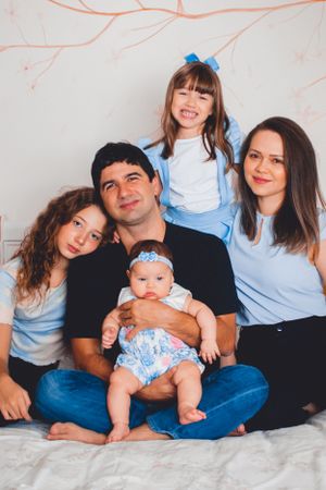 Family portrait with everyone coordinated in blue tones against white background.