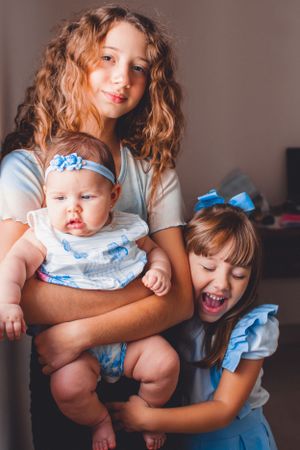Siblings pose with baby wearing matching blue outfits in candid family photo.