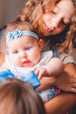 Candid moment of baby with blue floral headband being held and admired.