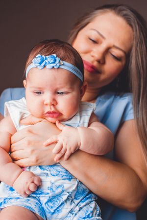 A tender moment between mother and baby wearing light blue clothing and accessories.