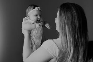 Black and white image of baby being lifted up during intimate moment.