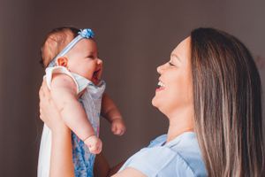 Mother holding and snuggling with baby dressed in light blue outfit.