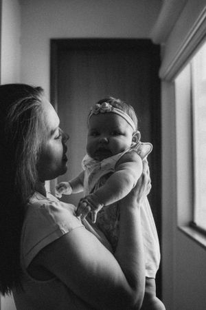 Black and white portrait of maternal bonding near a window.