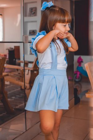 Young child in light blue dress twirling and playing in a home setting.