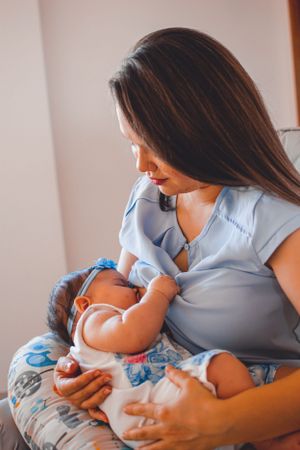 Intimate moment between mother and infant wearing matching light blue outfits.