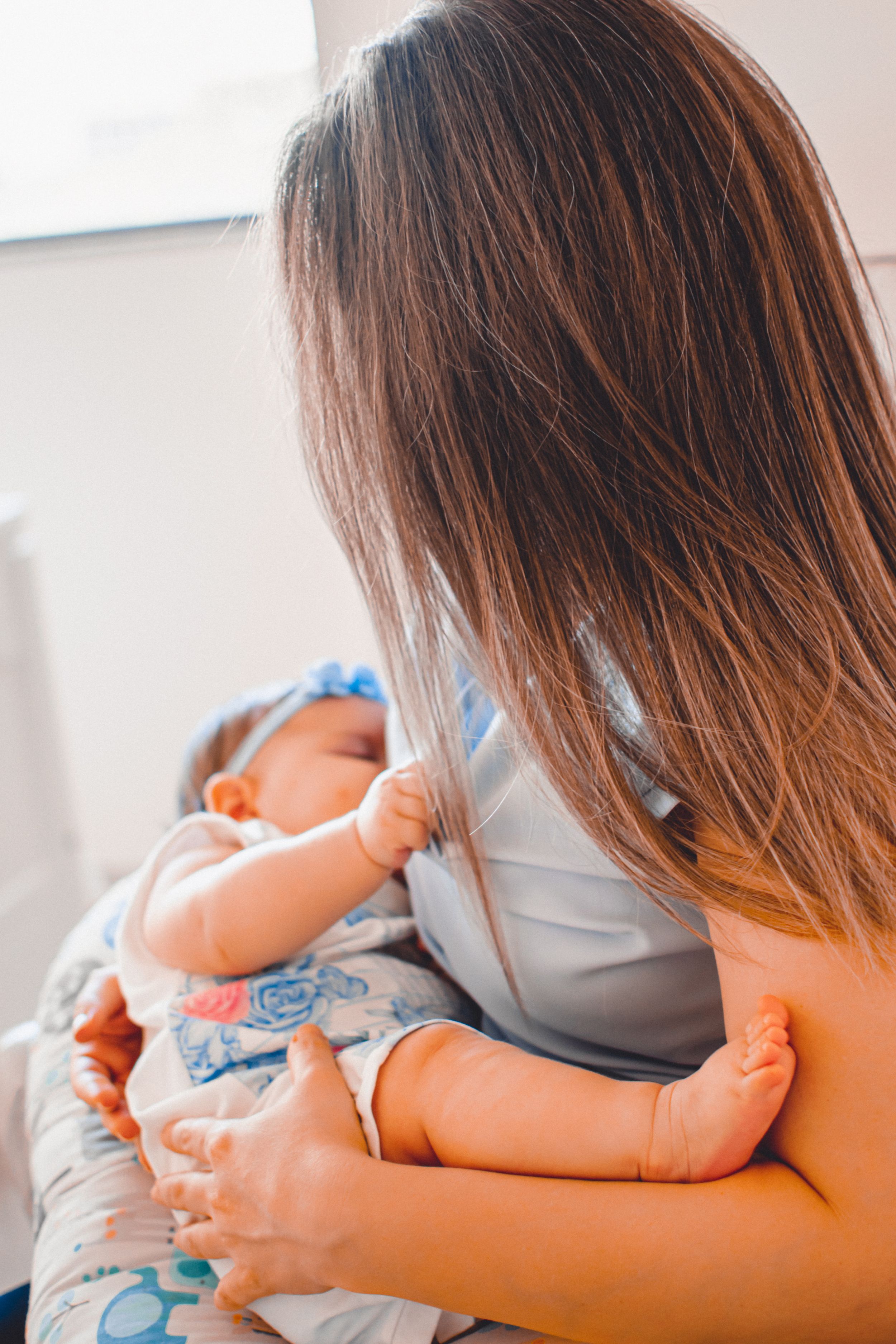 Mother cradling baby wearing coordinated blue and white outfits.