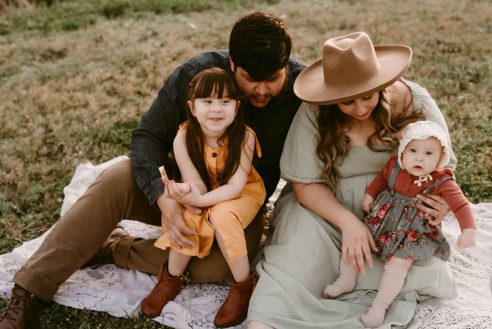 A family group sitting together on a picnic blanket in casual autumn attire.