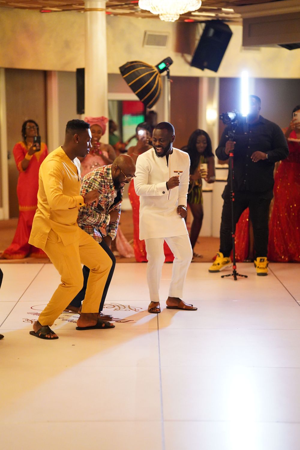 Celebratory dance moment between guests wearing yellow and white suits at formal event.