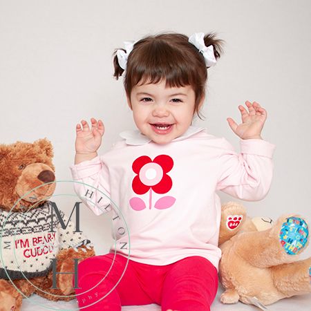 Color photo of young girl laughing with teddy bears
