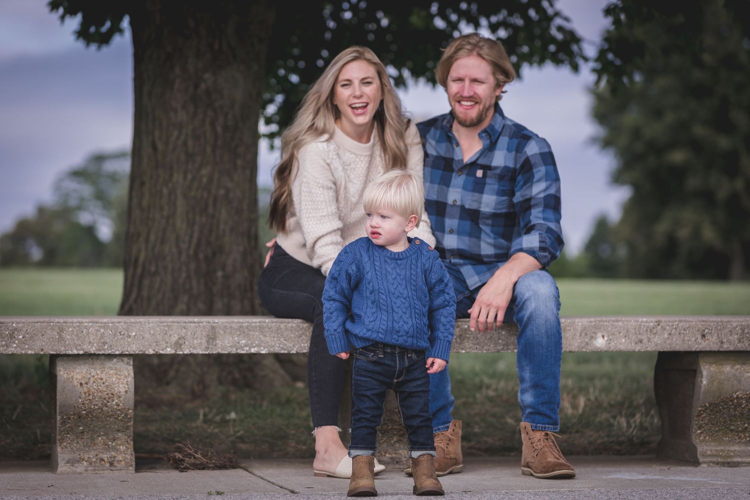 Family posing together on a wooden park bench outdoors.