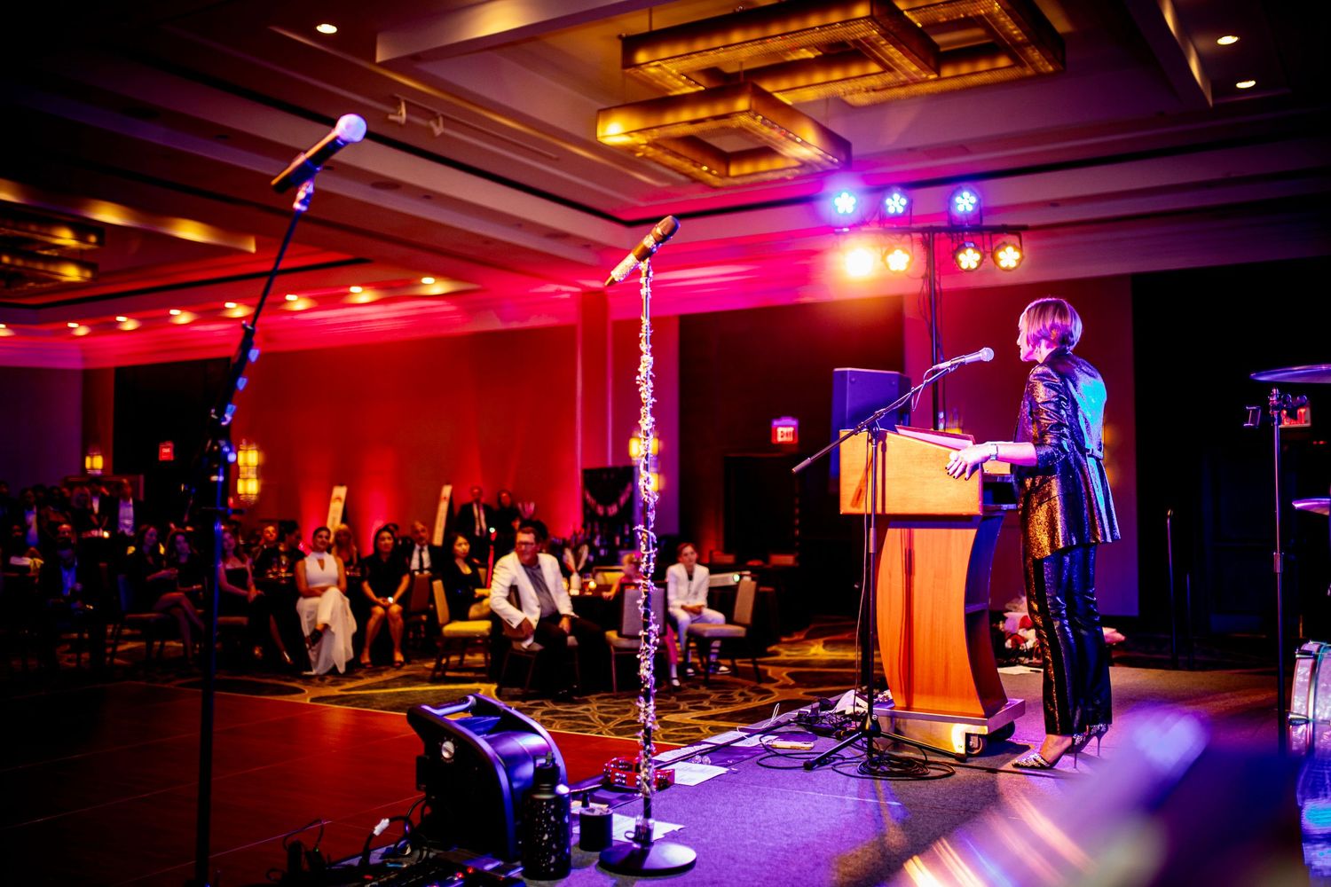 Concert venue interior with dramatic red and purple stage lighting effects.