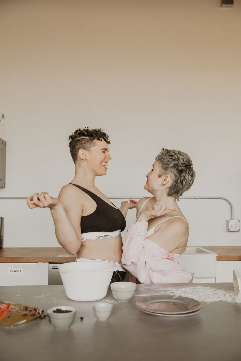 Playful couple in Calvin Klein underwear sharing a romantic moment while baking.