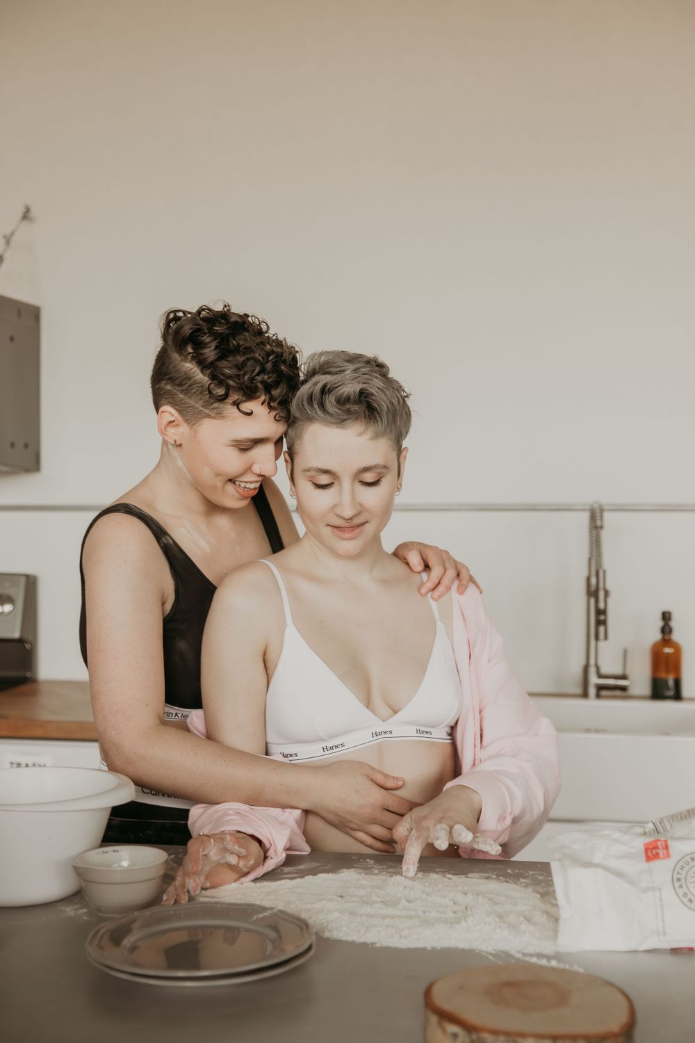 Couple baking together in kitchen while sharing intimate moment.
