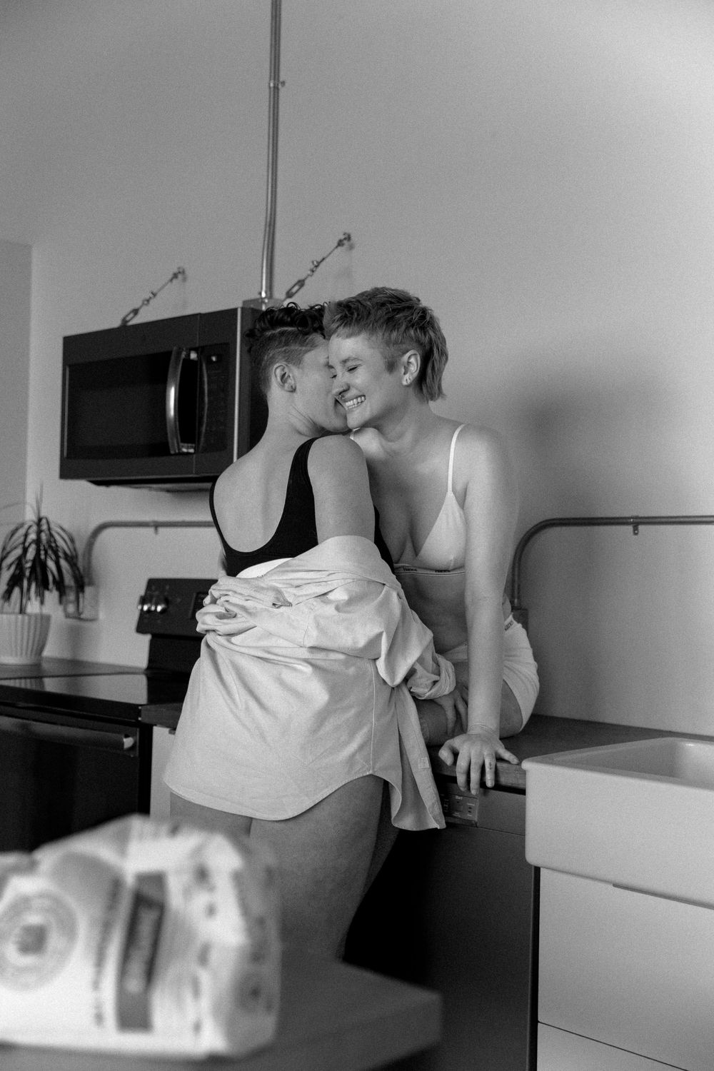 Candid black and white moment of affection in a home kitchen setting.