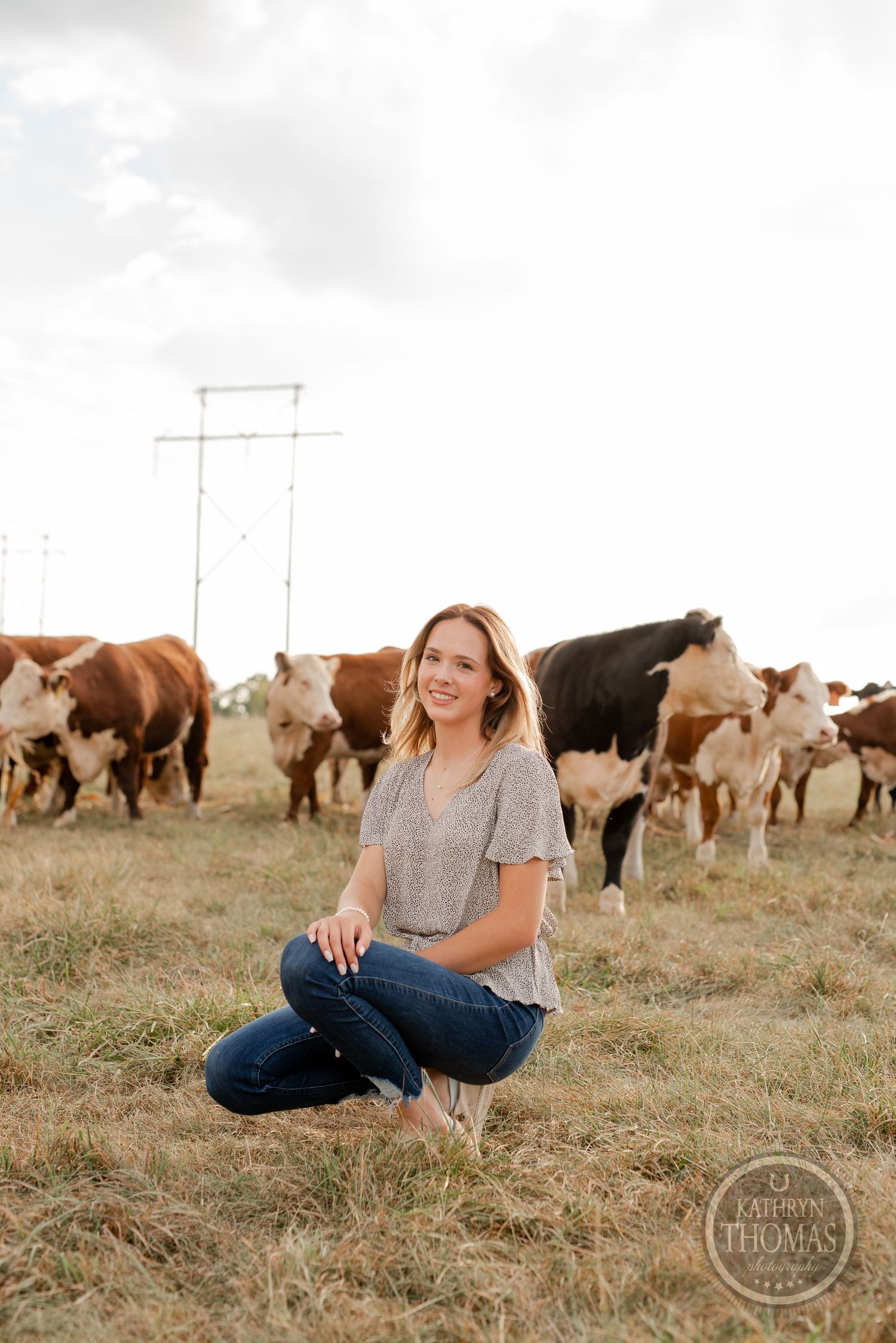 Rural outdoor portrait with grazing cattle herd in background.