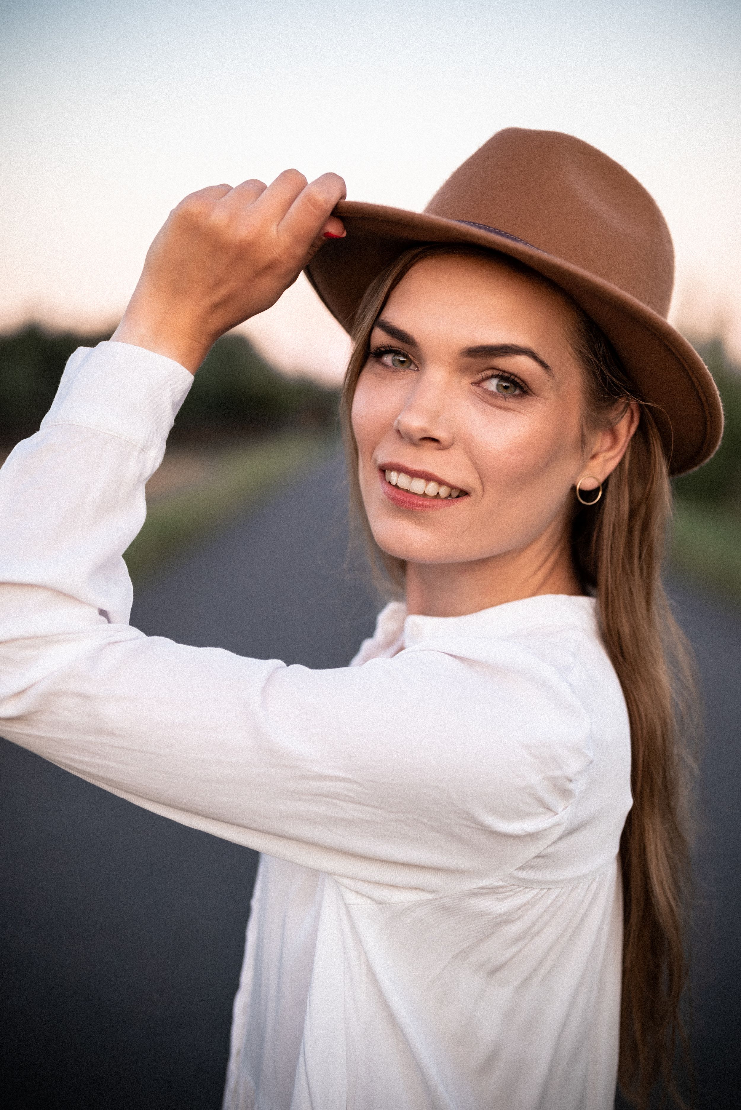 Country style portrait in white shirt and brown hat at sunset.