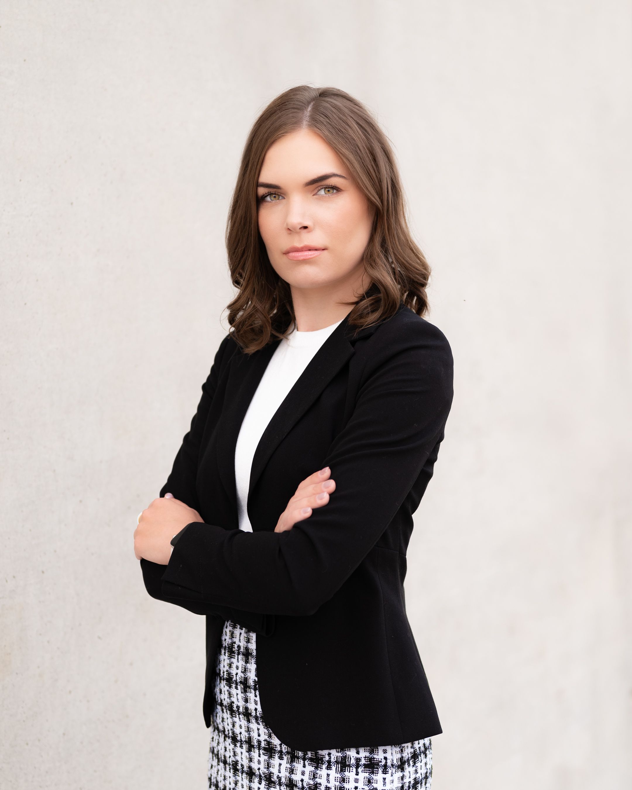 Professional business look featuring a black blazer and houndstooth skirt against white background.