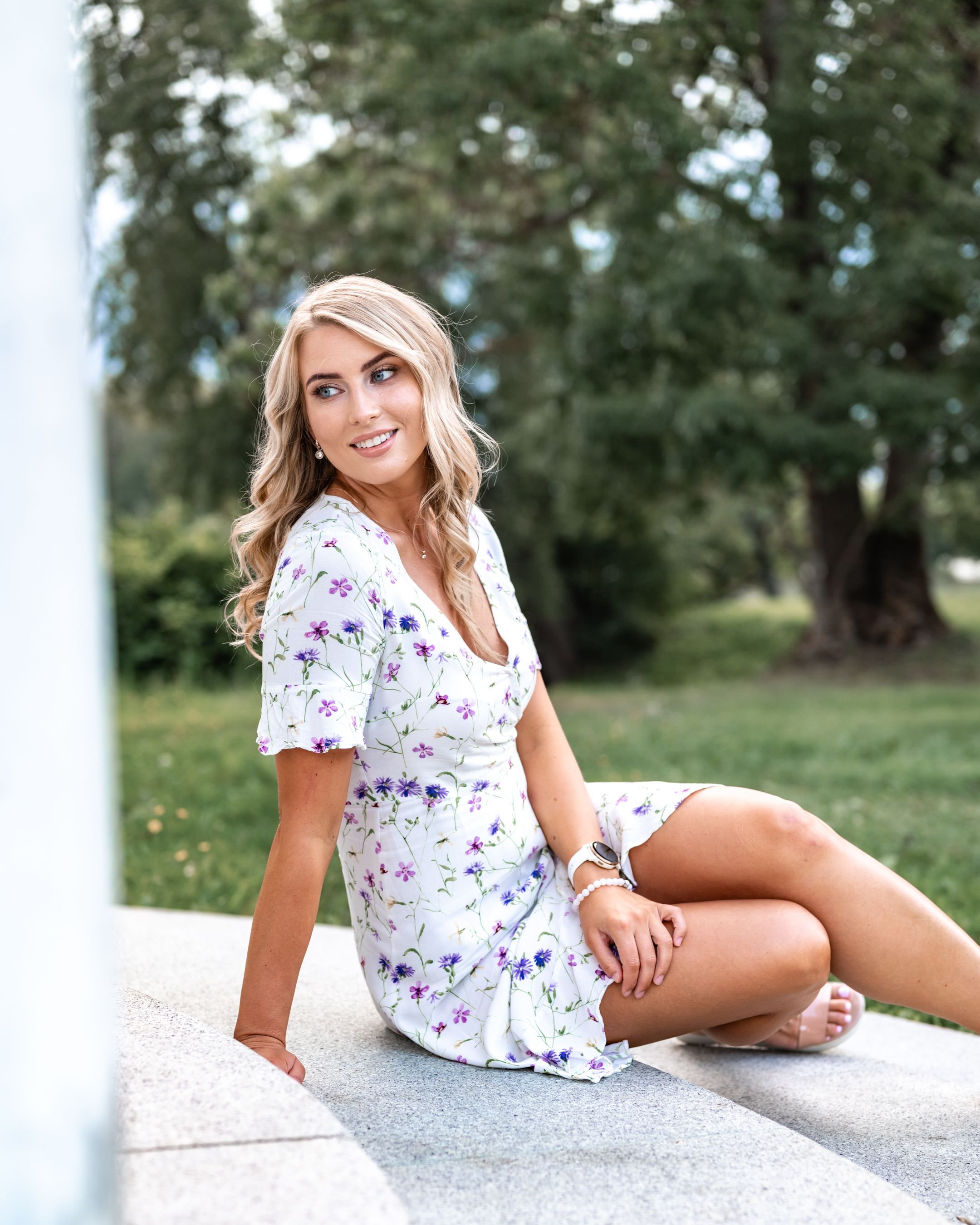 A feminine floral dress is showcased in a sunny outdoor setting.