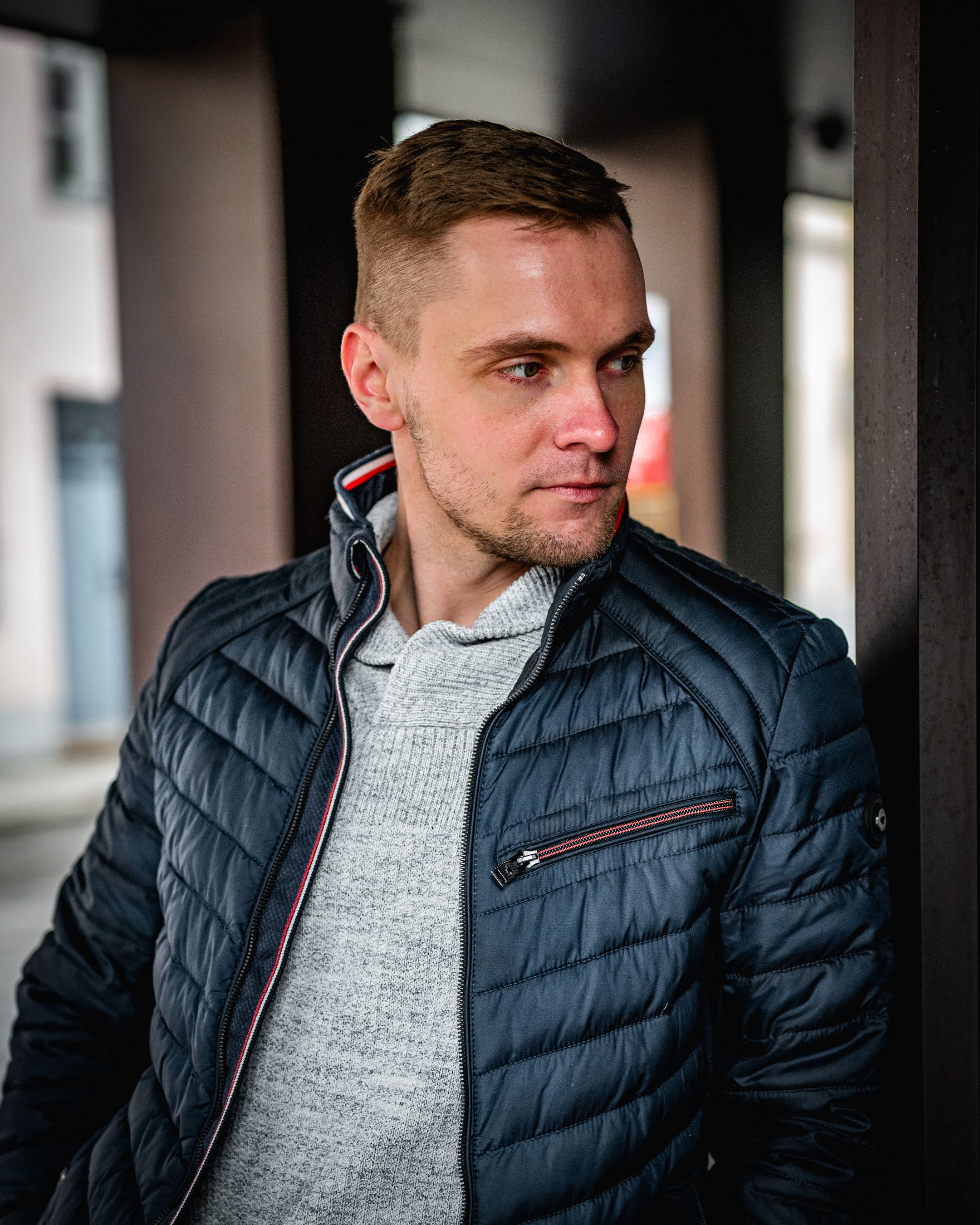 Casual portrait in grey sweater and navy puffer jacket.