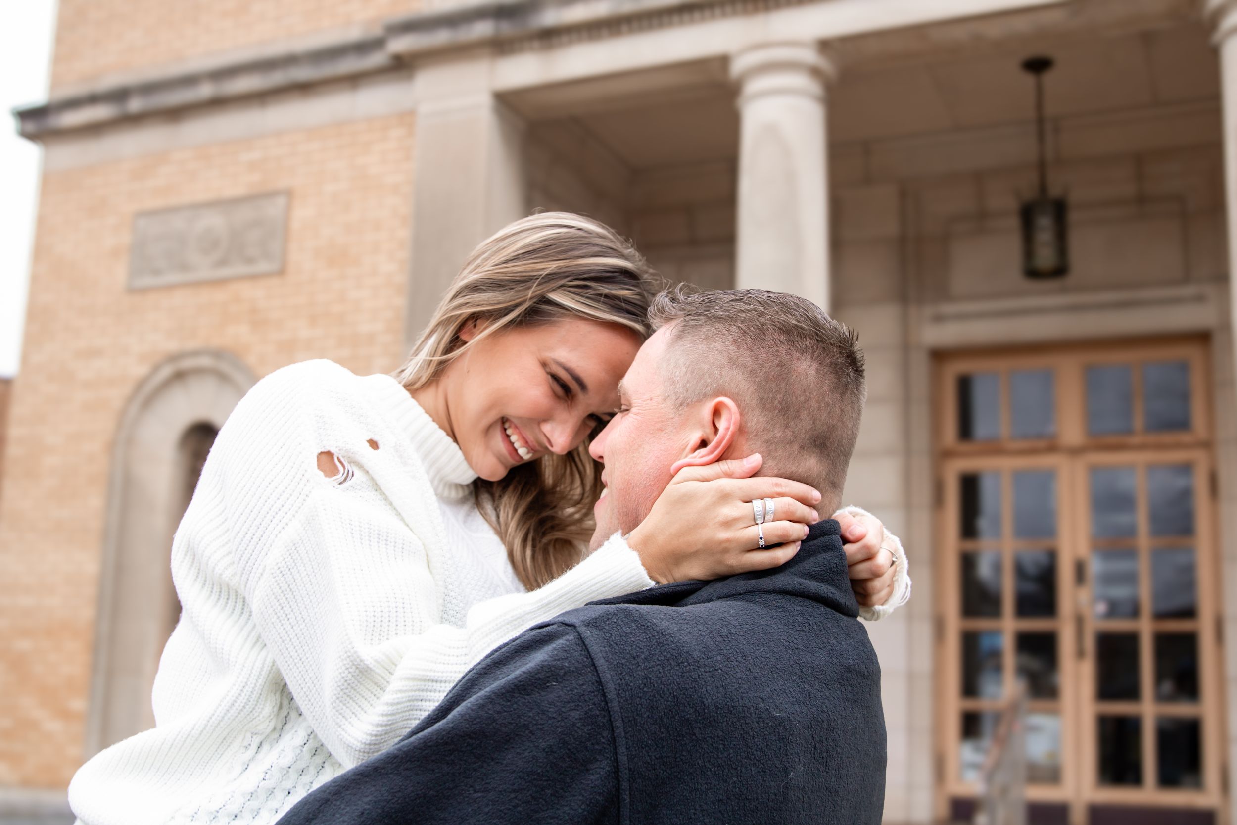 A happy couple in love, hugging in downtown,  captured by Box of Sunshine Studios