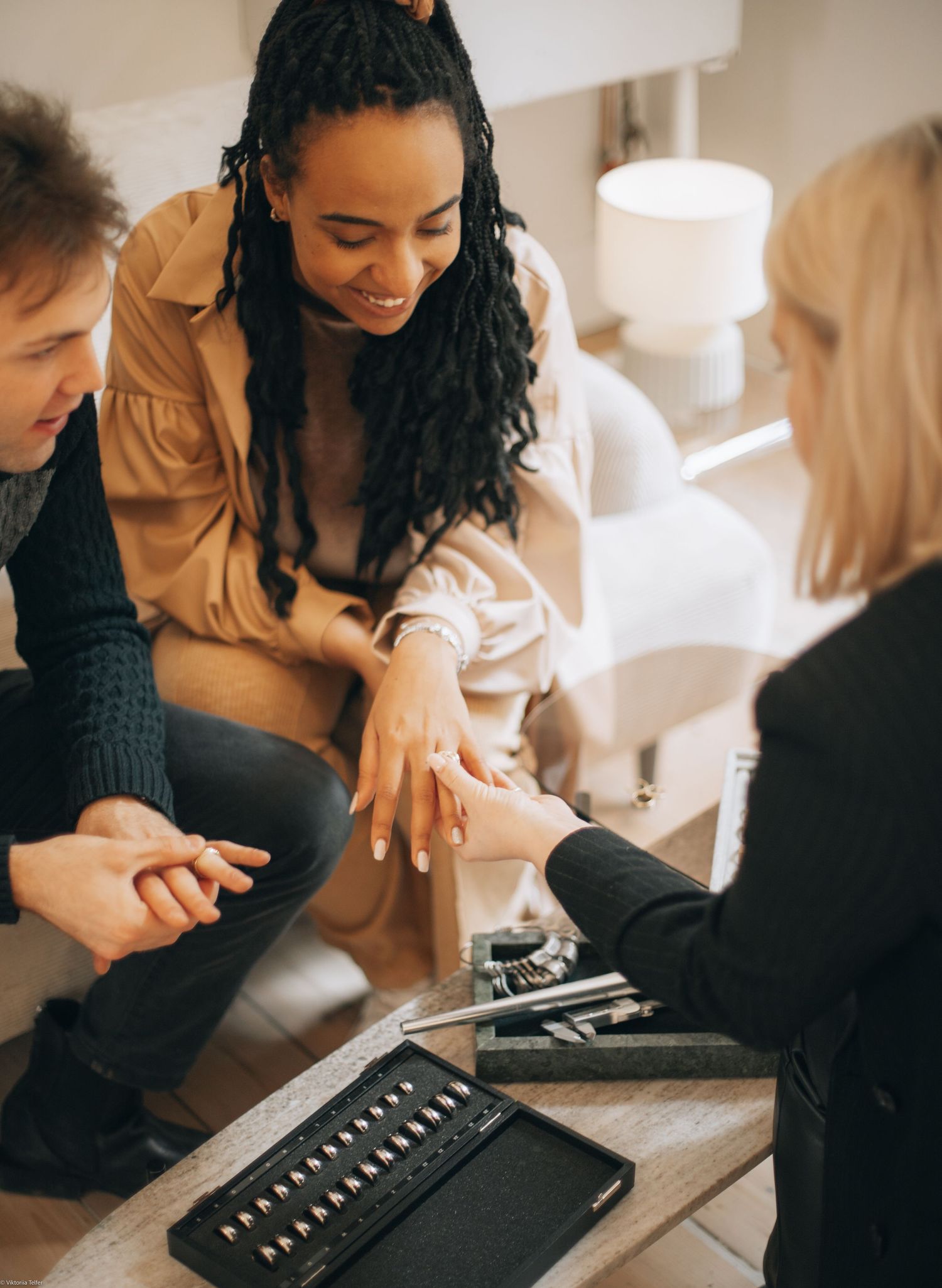 Group examining vintage jewelry pieces laid out on table during casual gathering.