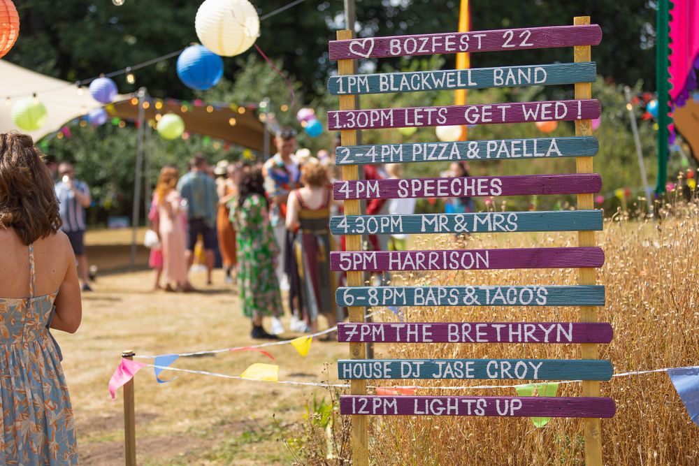 A colourful announcement board listing the order of the day at a music festival themed wedding.