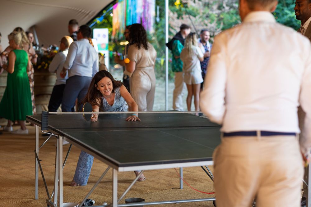 A woman reaches over a table tennis table to make a shot. One of a number of wedding games available on the day.
