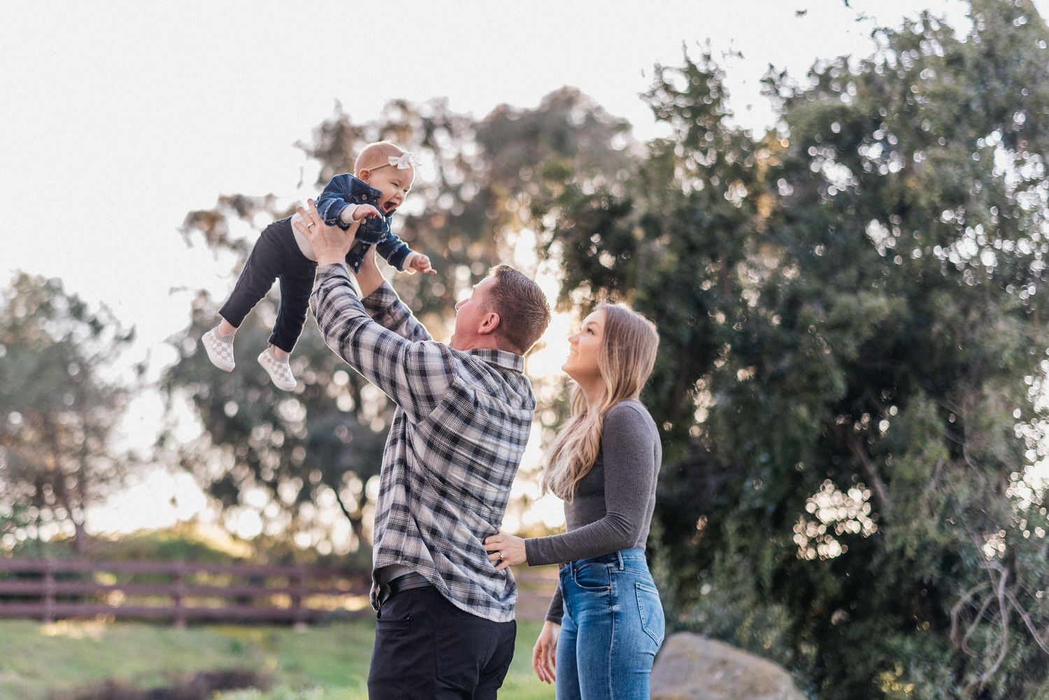 A playful moment captured outdoors as a small child is lifted high into the air.