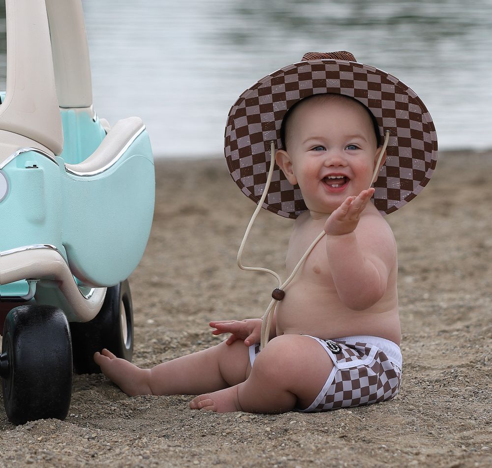 Toddler a big smile sitting on the beach for a birthday photo in Oakland County