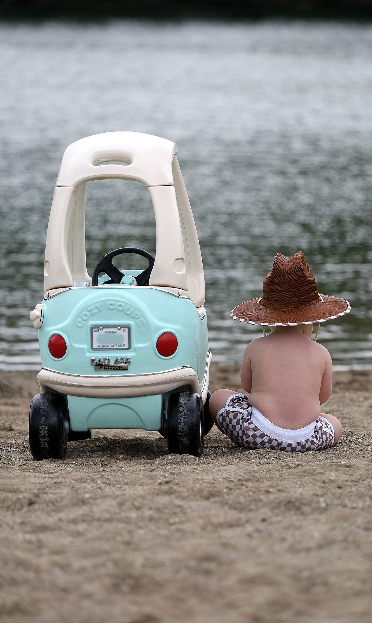Toddler sitting on a beach in South Lyon, MI with coupe car for his birthday photo