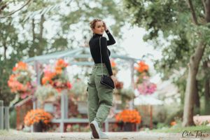 Stylish young woman in green cargo pants and black top poses confidently in a colorful autumn park.