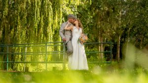 Romantic couple sharing a tender kiss in a lush green garden during their wedding ceremony.
