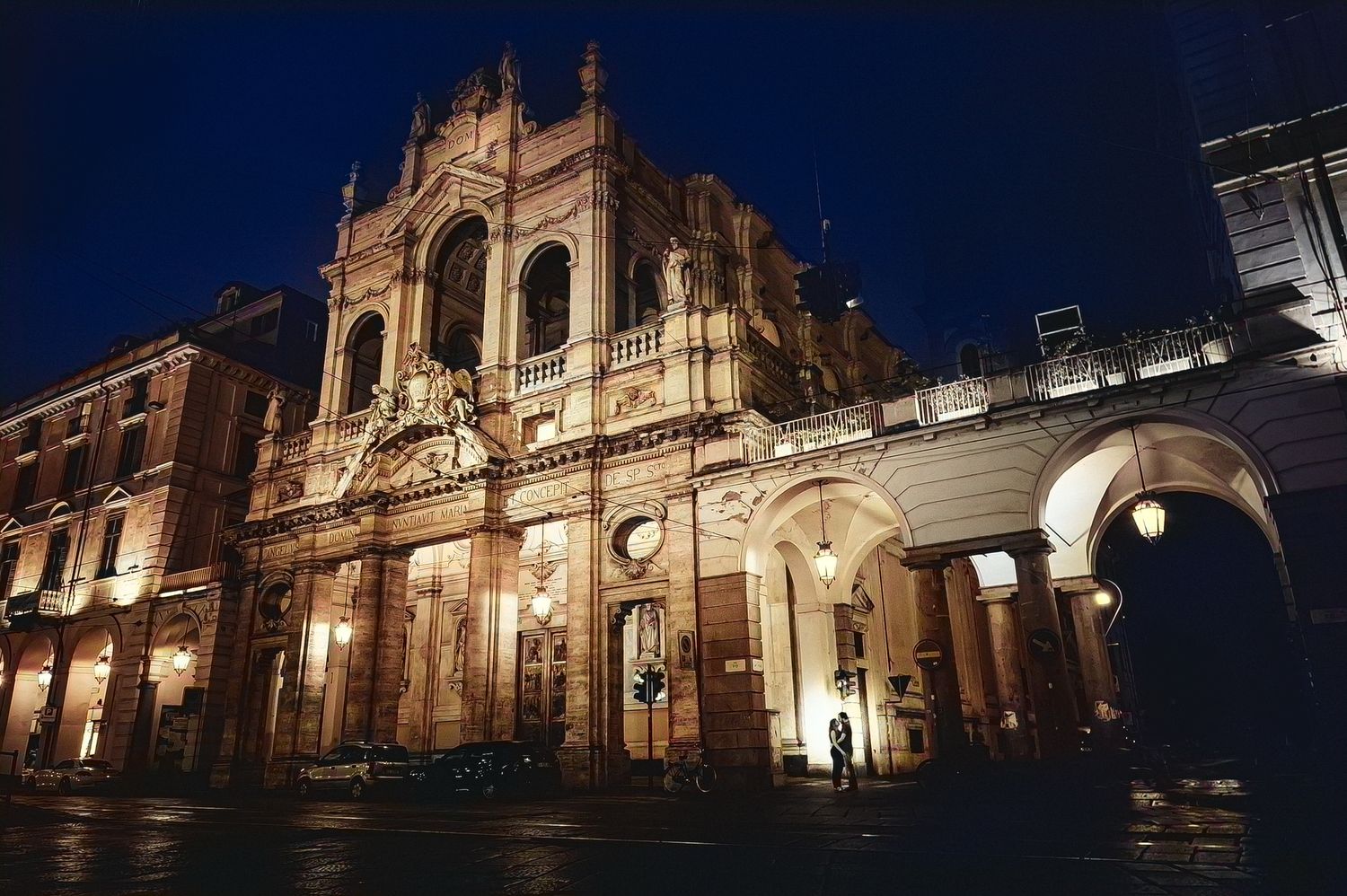 Ornate historic theater building illuminated at night with dramatic architectural details and warm golden lighting.