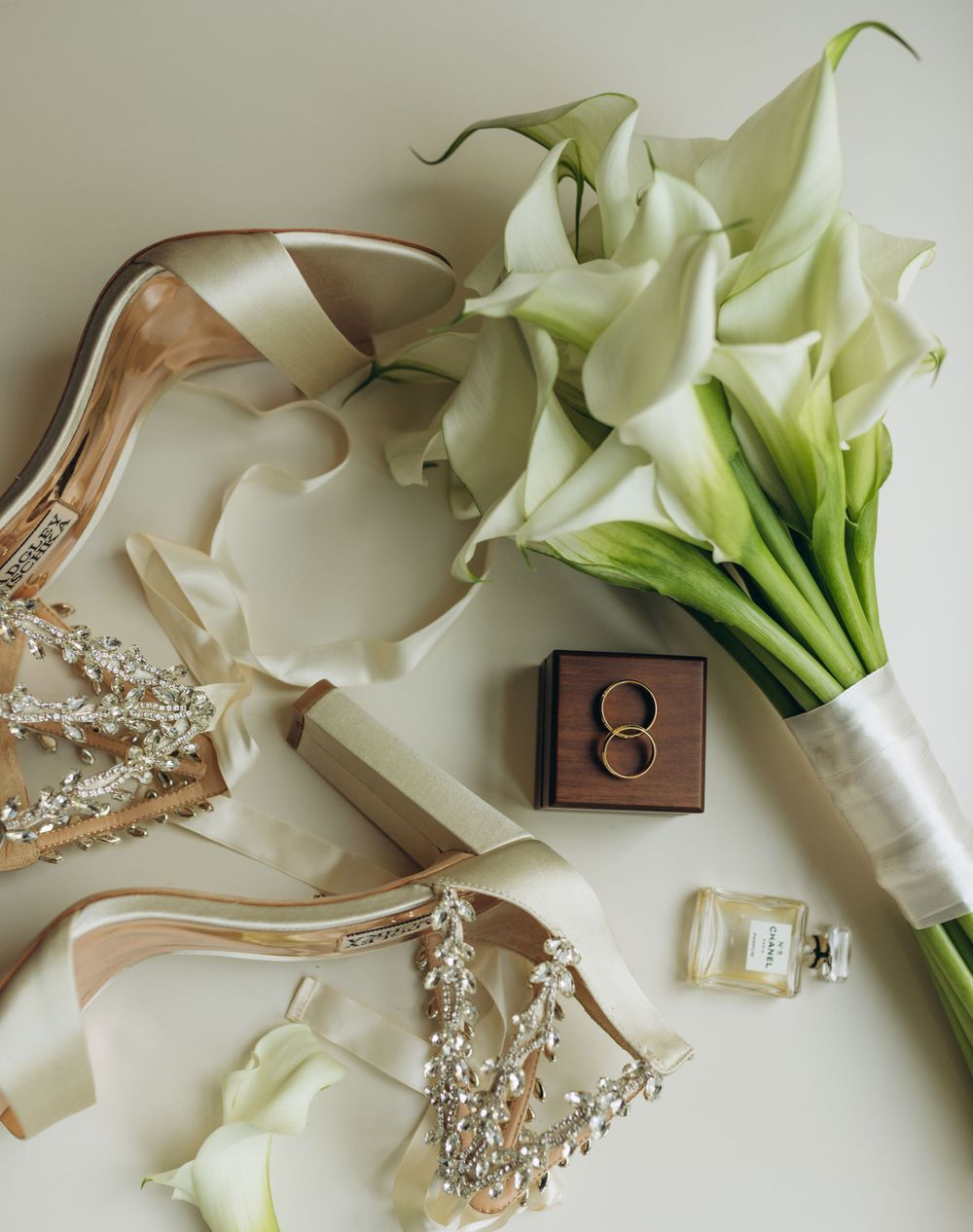 Bridal details with crystal-embellished heels, calla lily bouquet and wedding rings.