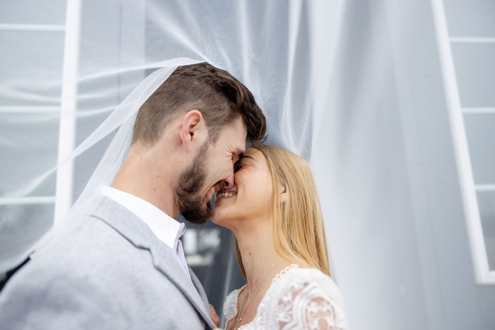 A romantic wedding couple shares an intimate moment against a white backdrop.