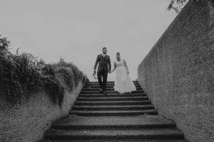 Black and white photo of bride and groom descending stone staircase on wedding day.